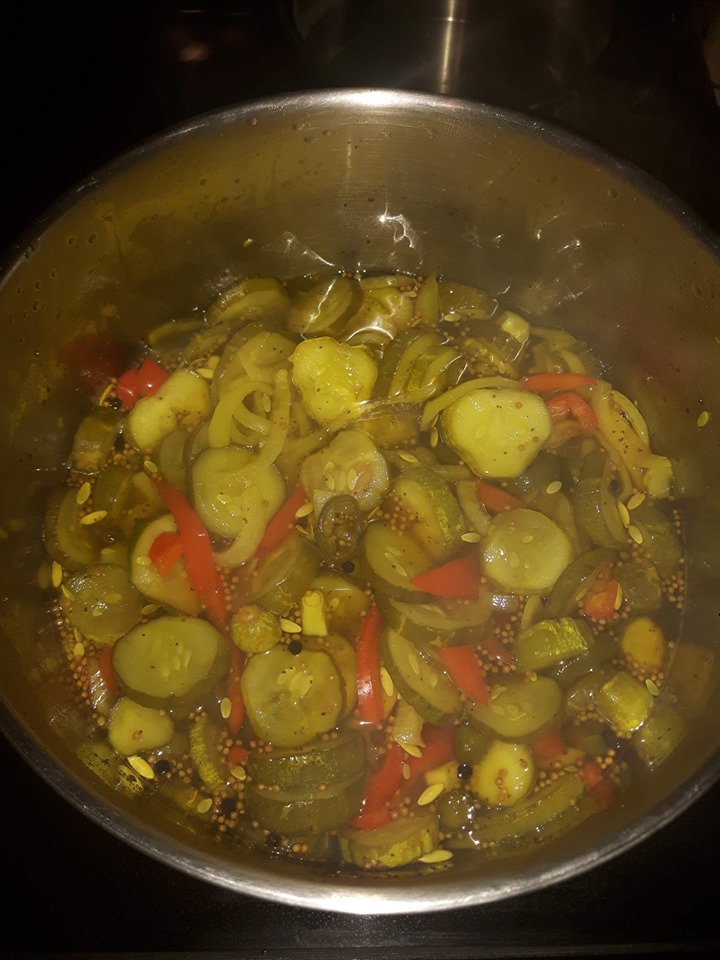 Cut up cucumbers making pickles in a large steel pot