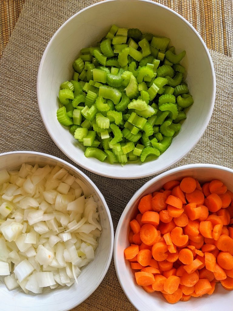 French mirepoix cut up carrots, celery and onion in bowls